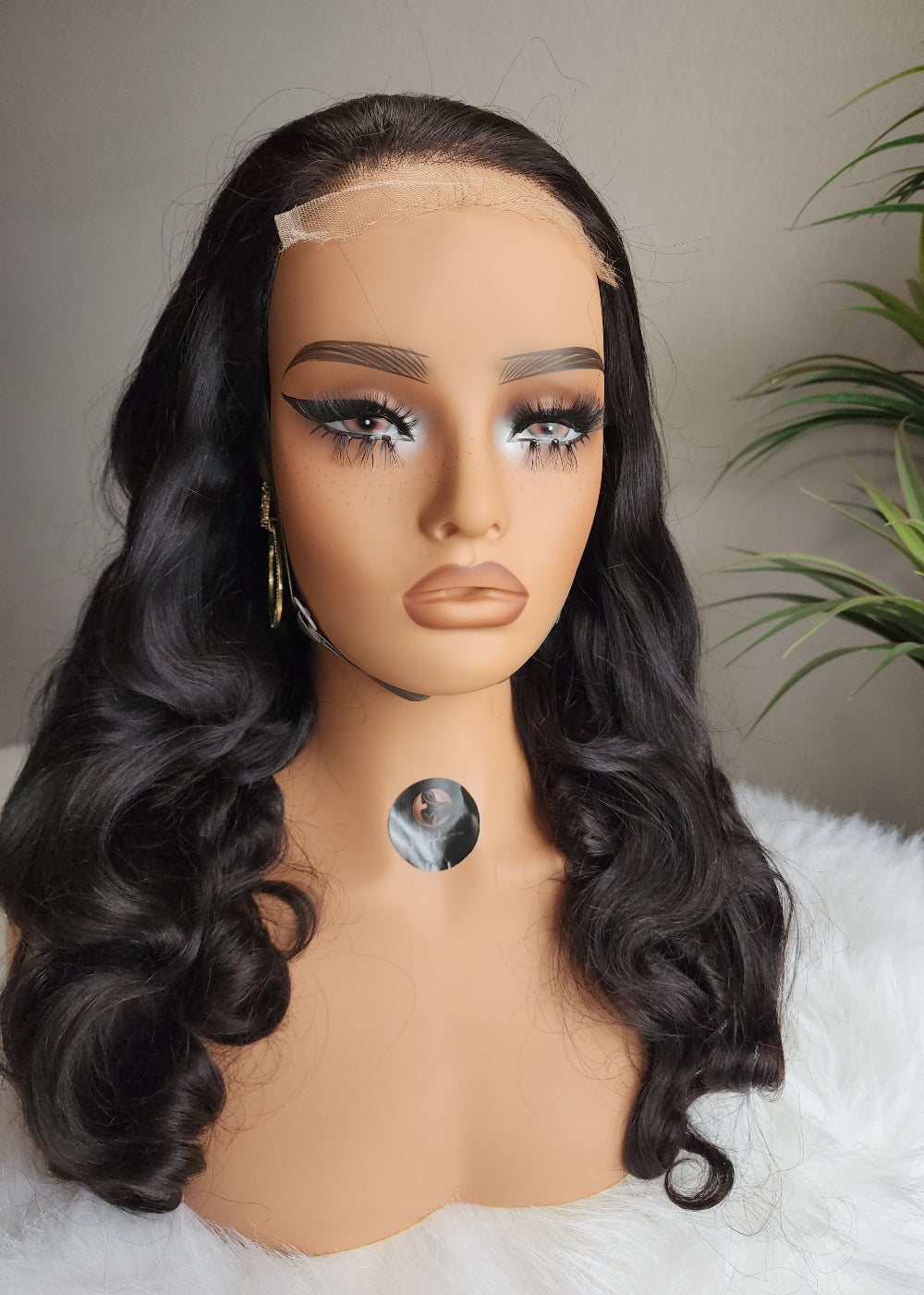 Mannequin head with long black wavy hair on a white surface.